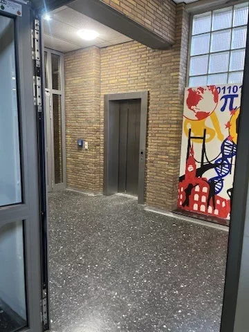 Modernisierte Aufzugst&uuml;r im Foyer eines &ouml;ffentlichen Geb&auml;udes mit Klinkerwand