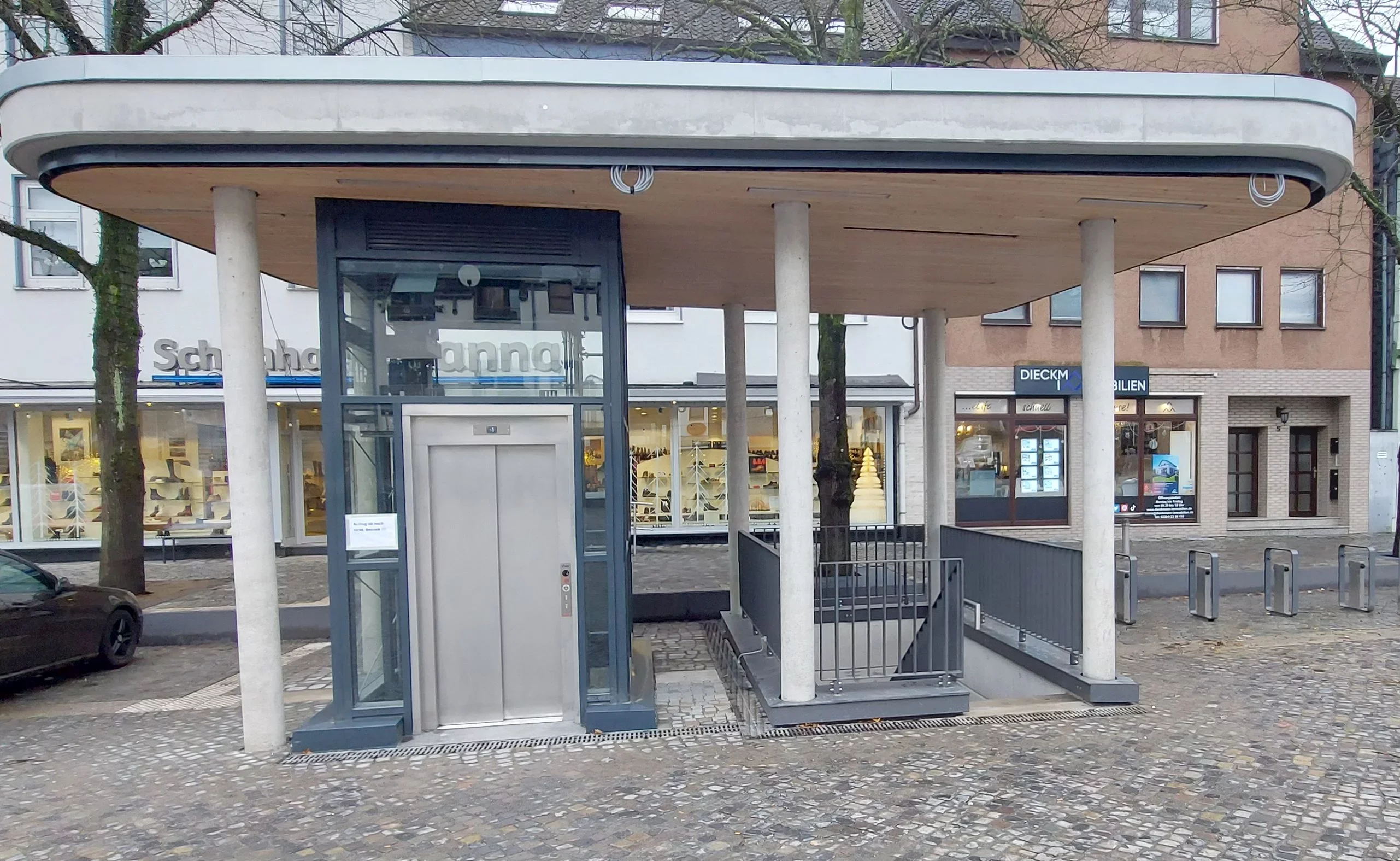 Freistehender &ouml;ffentlicher Aufzug mit Glasschacht unter einem Vordach in der Innenstadt