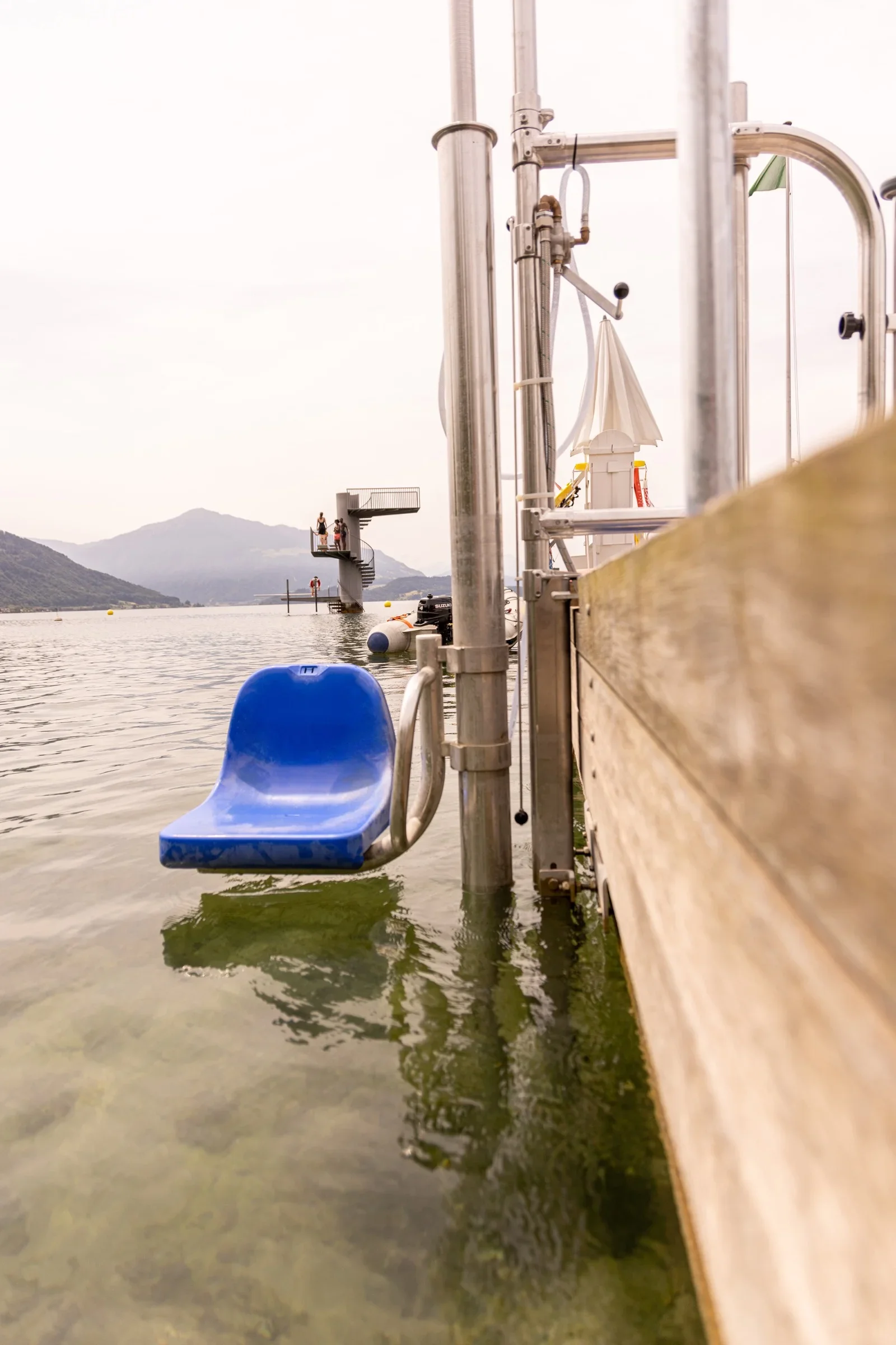 Poollift Delphin mit blauem Sitz an einem Badesteg, Sitz ins Seewasser abgesenkt