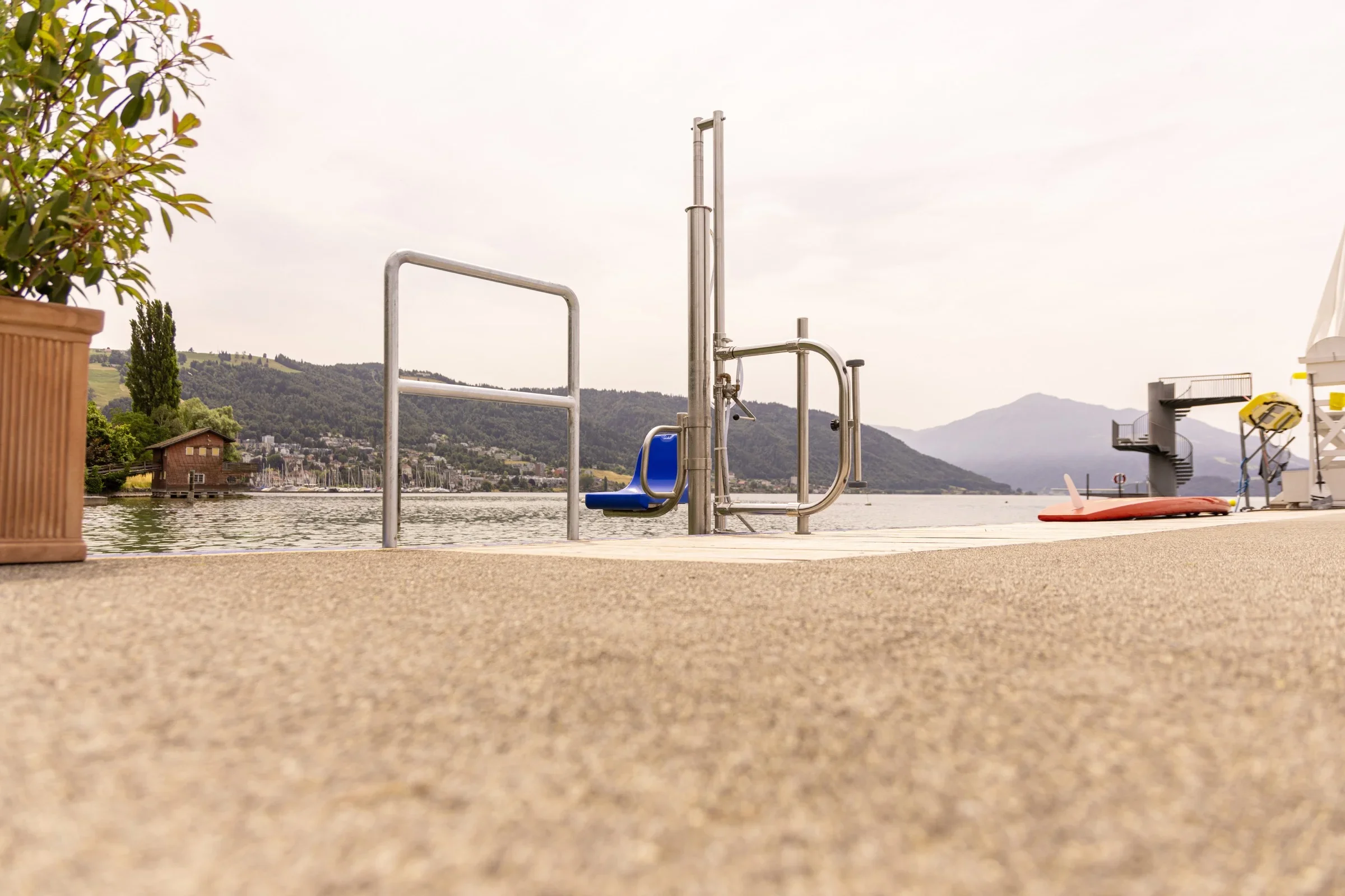 Poollift an einer Uferpromenade am See vor Bergpanorama
