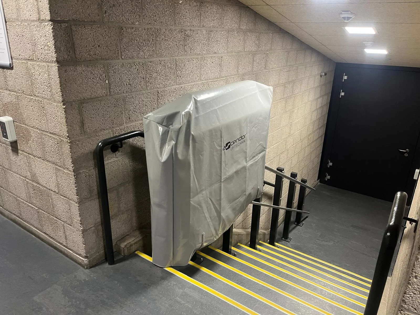Plattformlift mit Wetterschutzh&uuml;lle an einer Treppe im Untergeschoss
