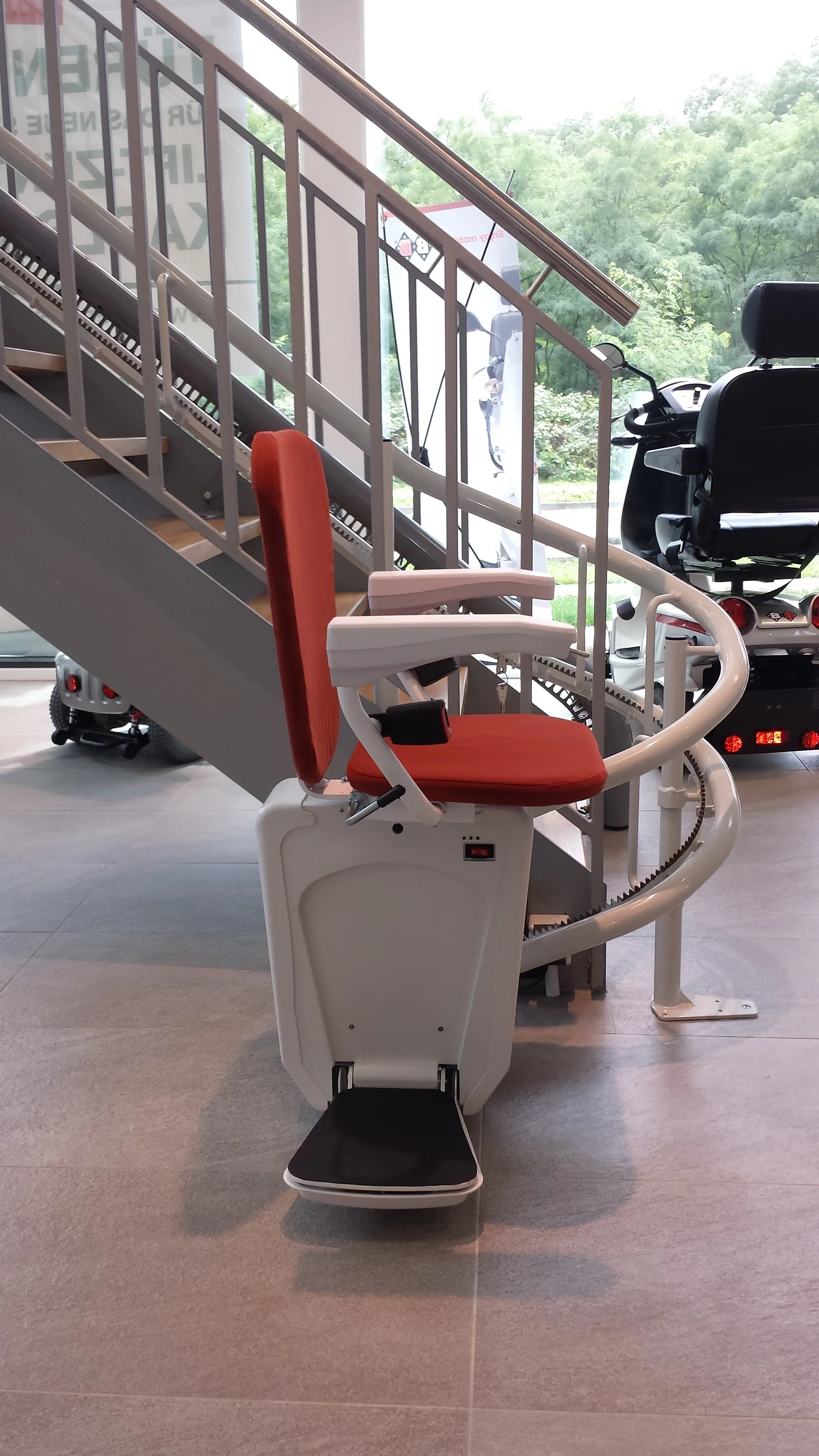 Sitztreppenlift mit rotem Polster an einer Stahltreppe