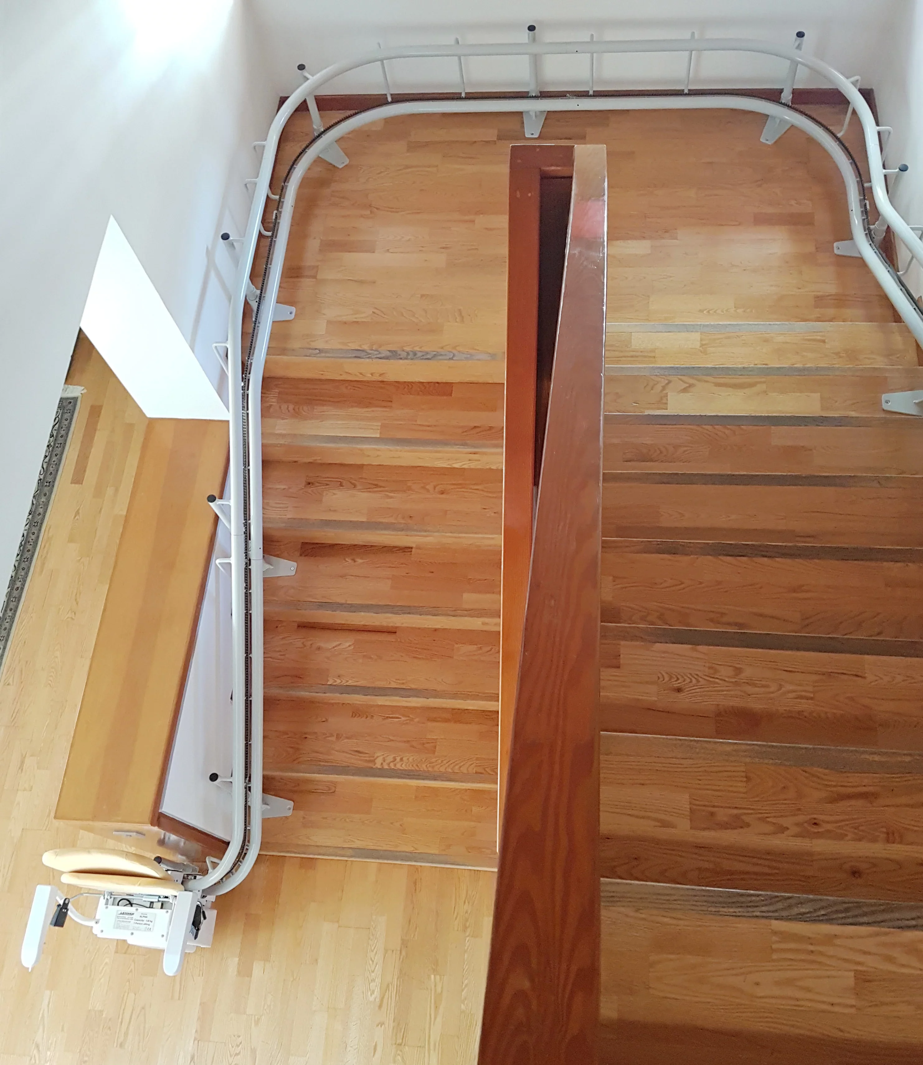 Fahrschiene eines Sitztreppenlifts entlang einer zweil&auml;ufigen Holztreppe, Draufsicht