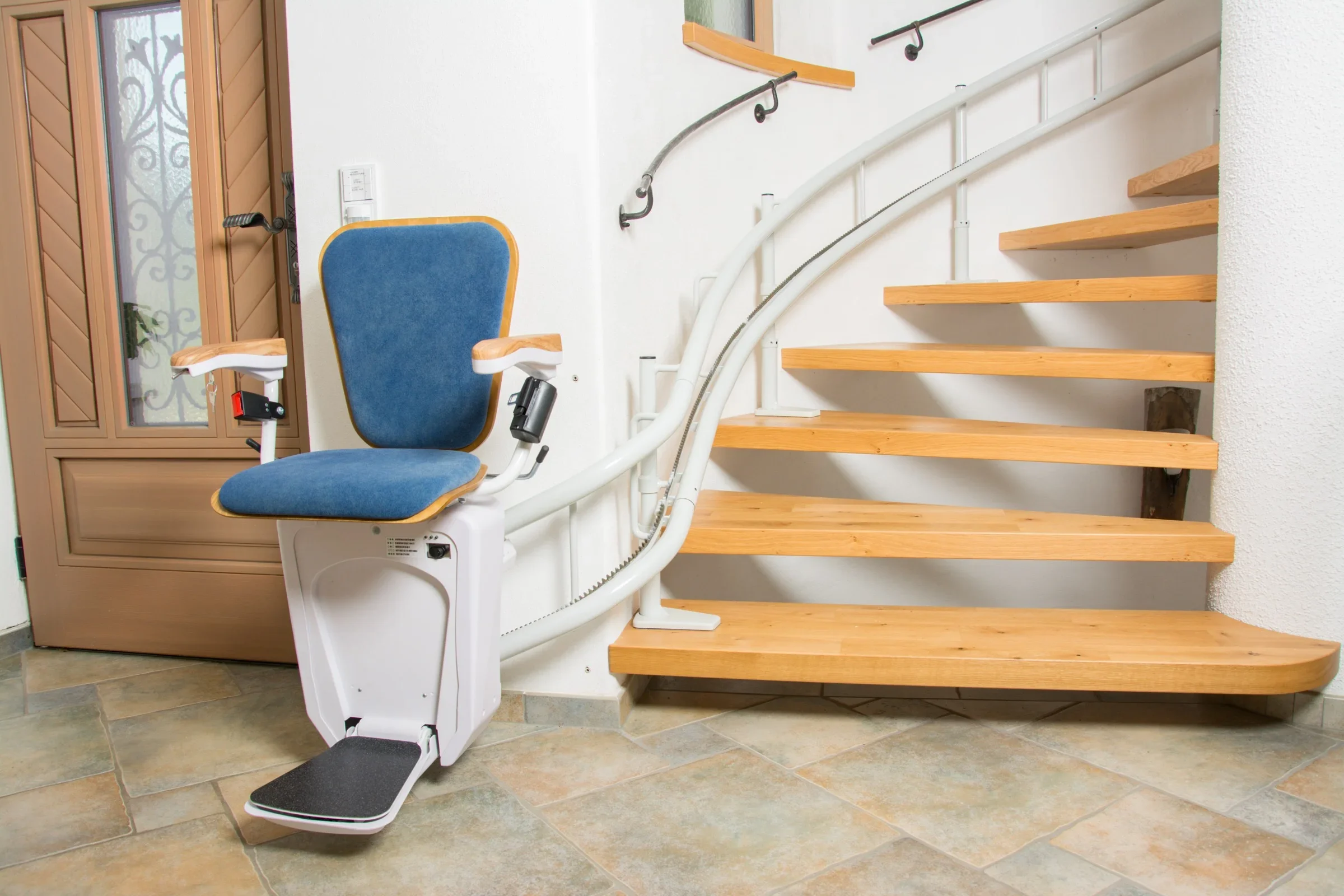 Sitztreppenlift mit blauem Polster und Kurvenschiene an einer Holztreppe