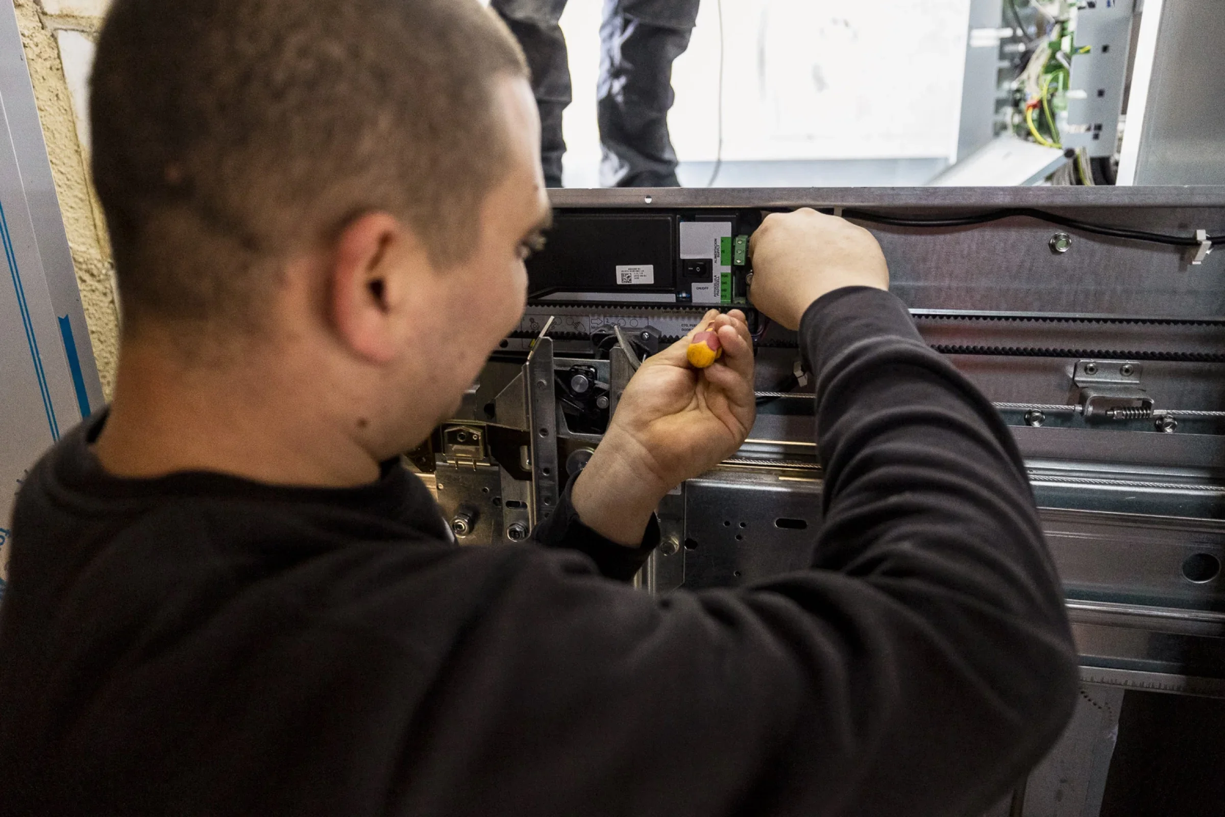 Techniker von ALPHA Aufzugsservice arbeitet am T&uuml;rantrieb einer Aufzugskabine