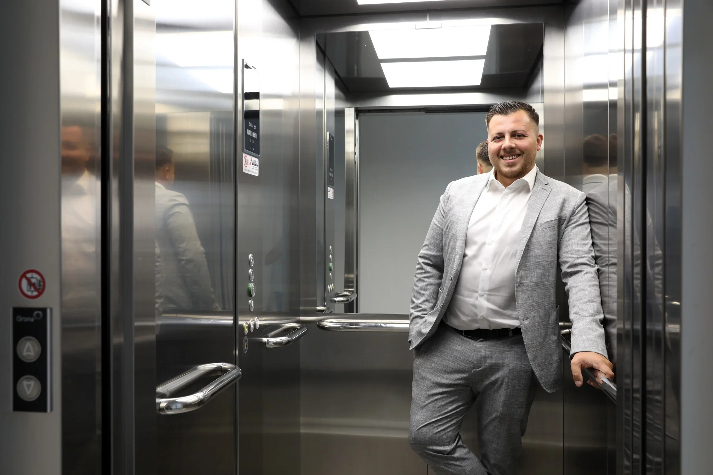 Mitarbeiter von ALPHA Aufzugsservice in einer Aufzugskabine aus Edelstahl