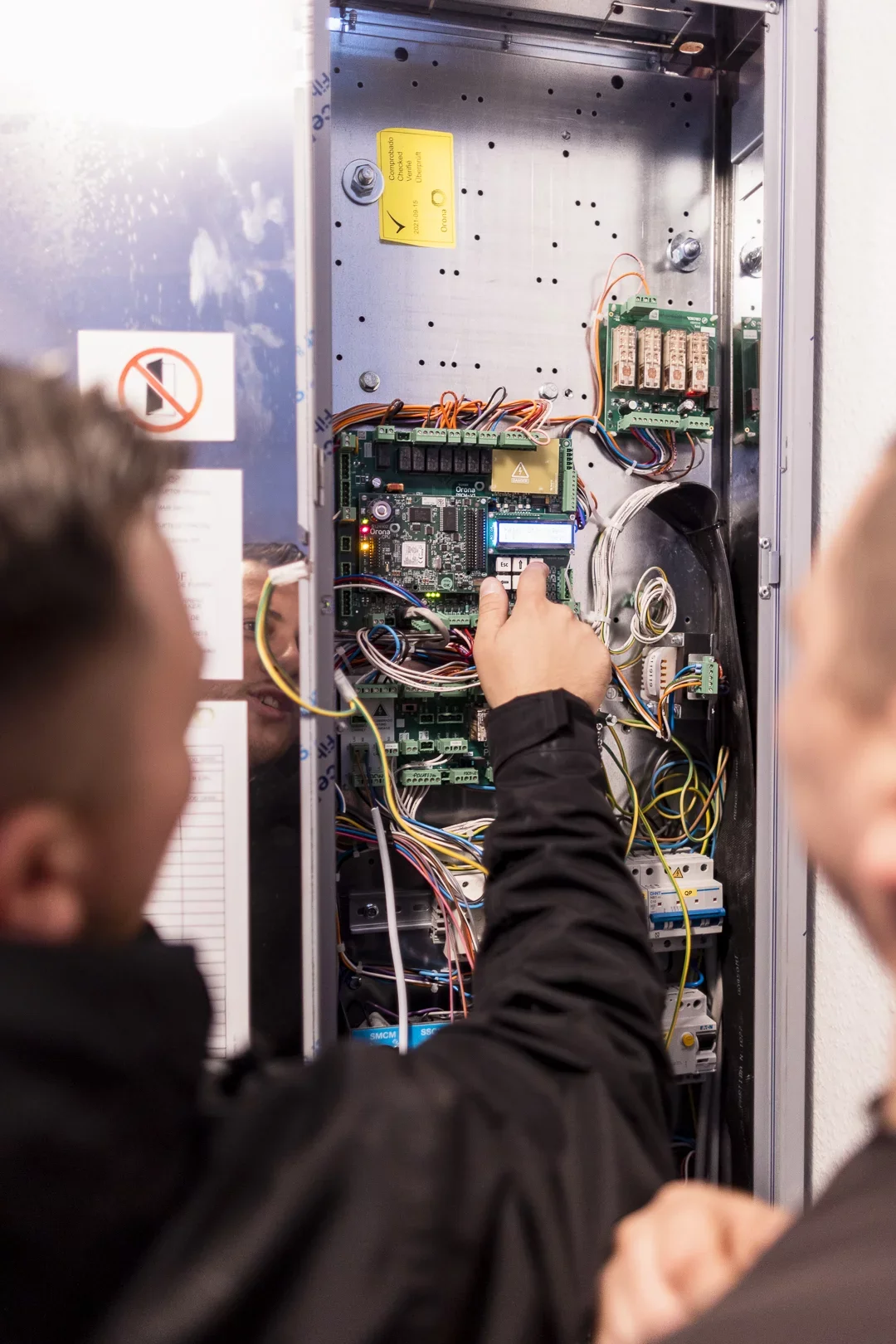 Techniker pr&uuml;ft die Aufzugssteuerung im ge&ouml;ffneten Schaltschrank