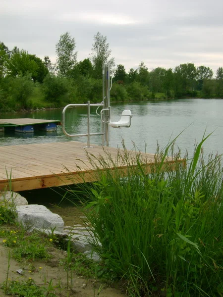 Poollift auf einem Holzsteg am Badesee mit Schilf