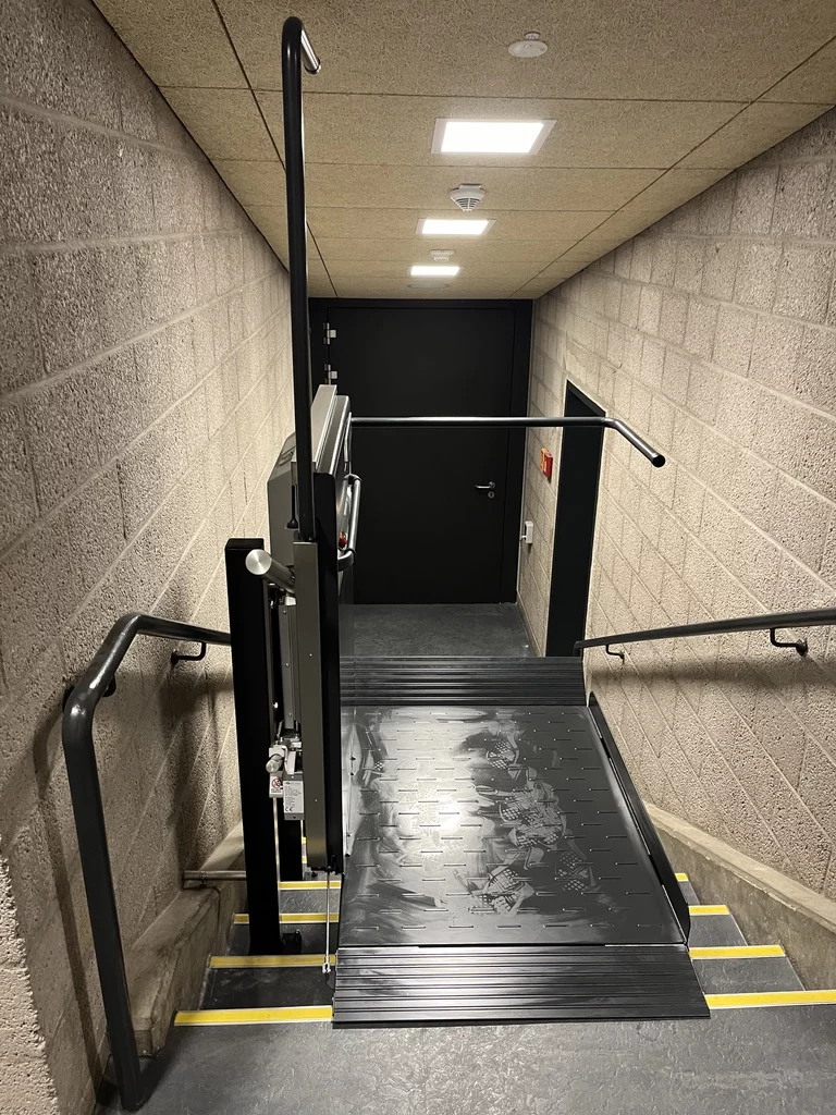 Plattformtreppenlift für Rollstuhlfahrer mit ausgeklappter Plattform an einer Innentreppe