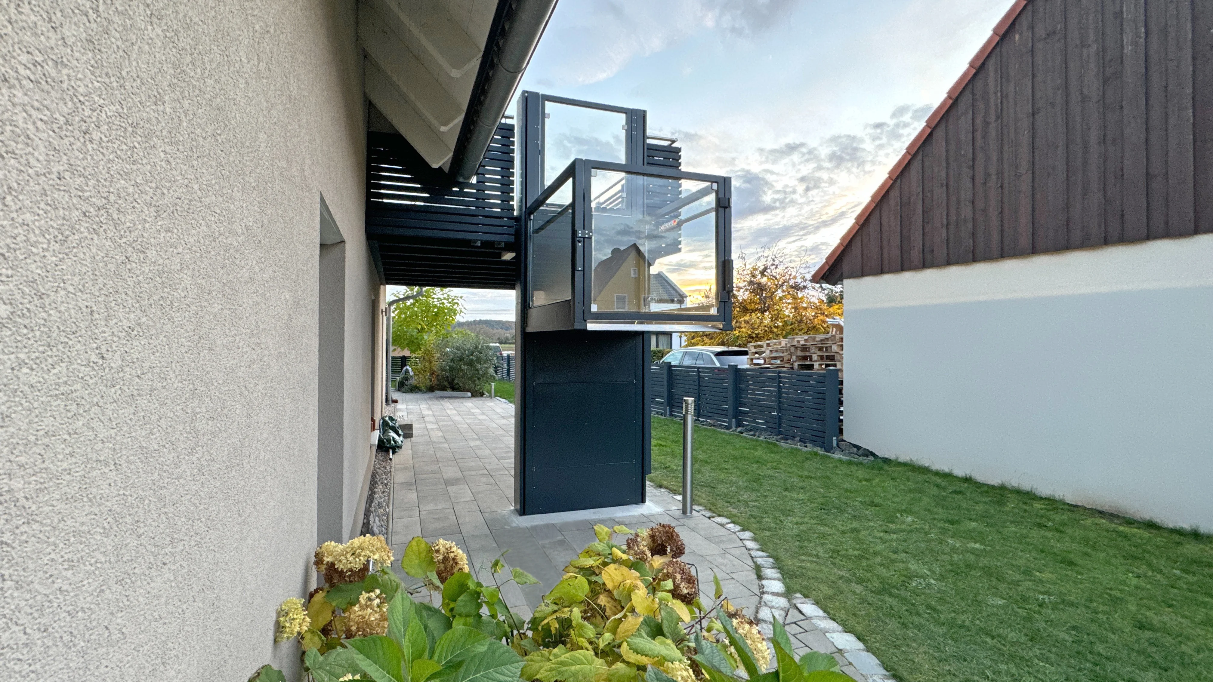 Vertikaler Plattformlift RB150 an der Hauswand eines Einfamilienhauses zum Balkon