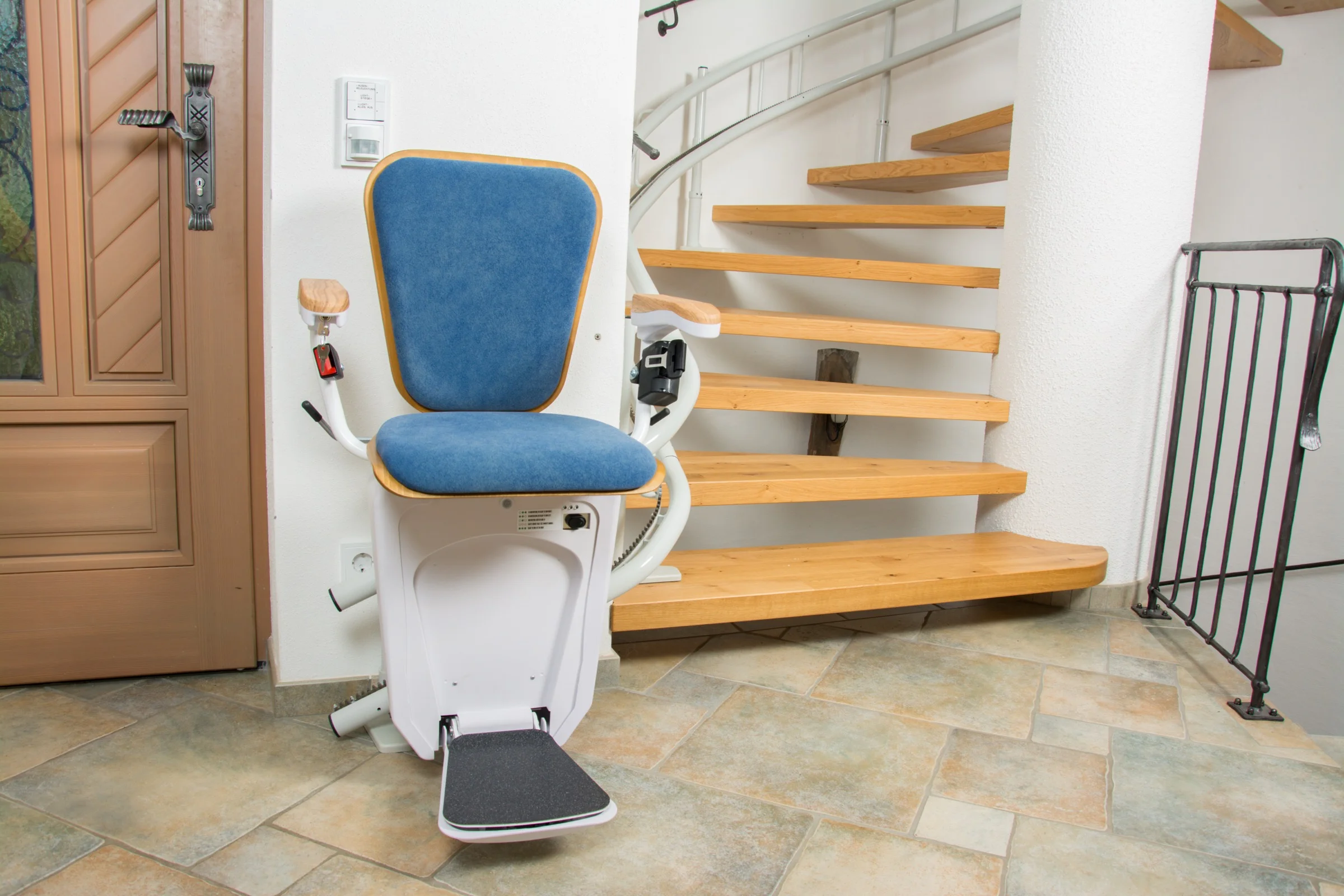 Sitztreppenlift mit blauem Polster an einer offenen Holztreppe im Eingangsbereich