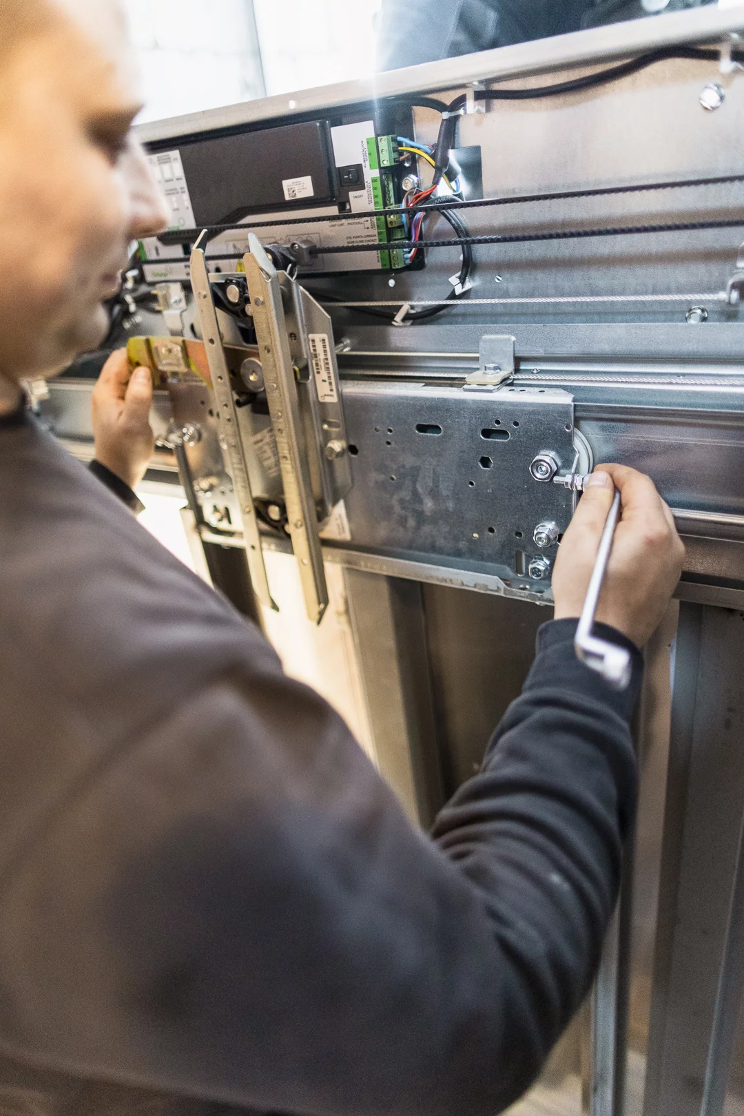 Techniker stellt bei der Aufzugswartung den Türantrieb ein