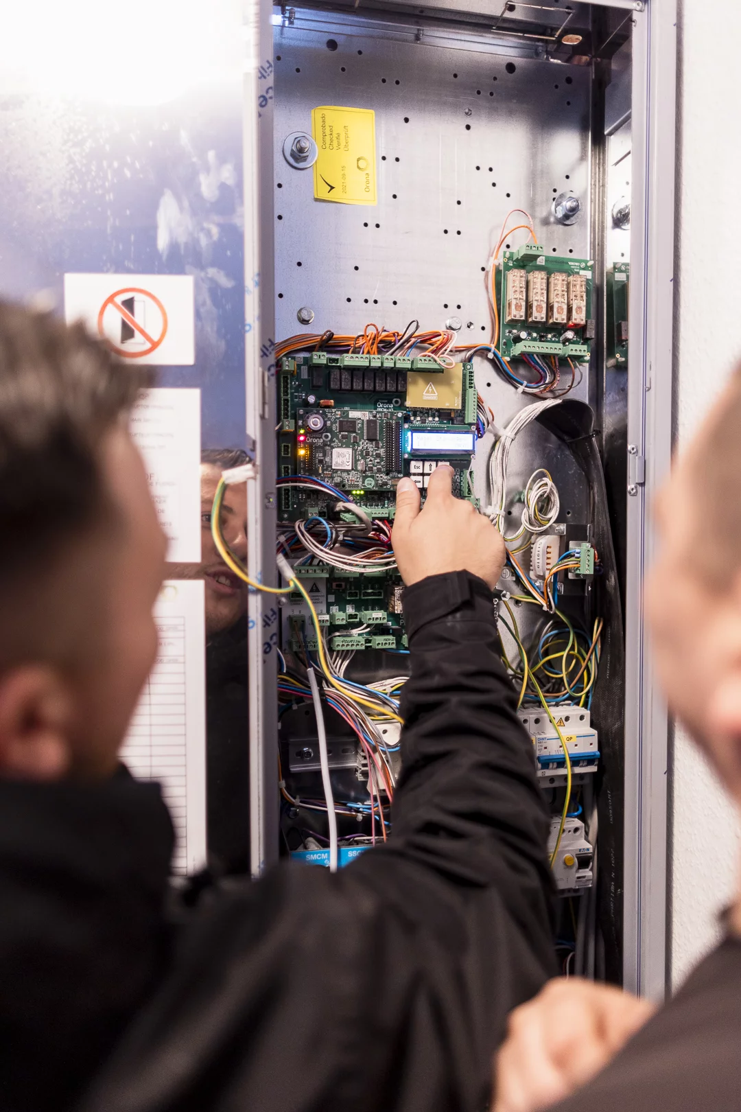 Techniker prüft die Aufzugssteuerung im geöffneten Schaltschrank